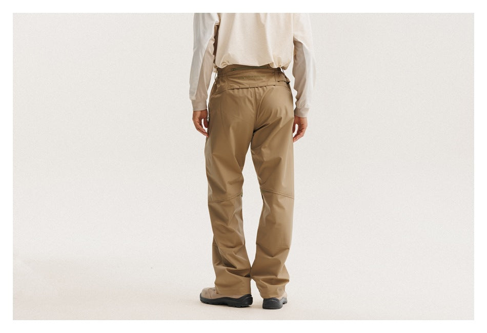 Back view of a person wearing tan pants with a wide waistband and articulated knee seams.