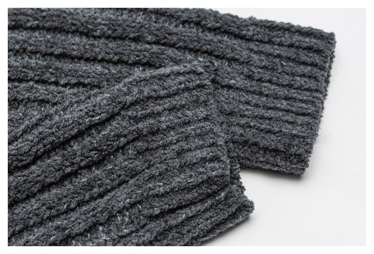 Close-up of a dark charcoal knit garment with thick raised diagonal texture and a ribbed edge.