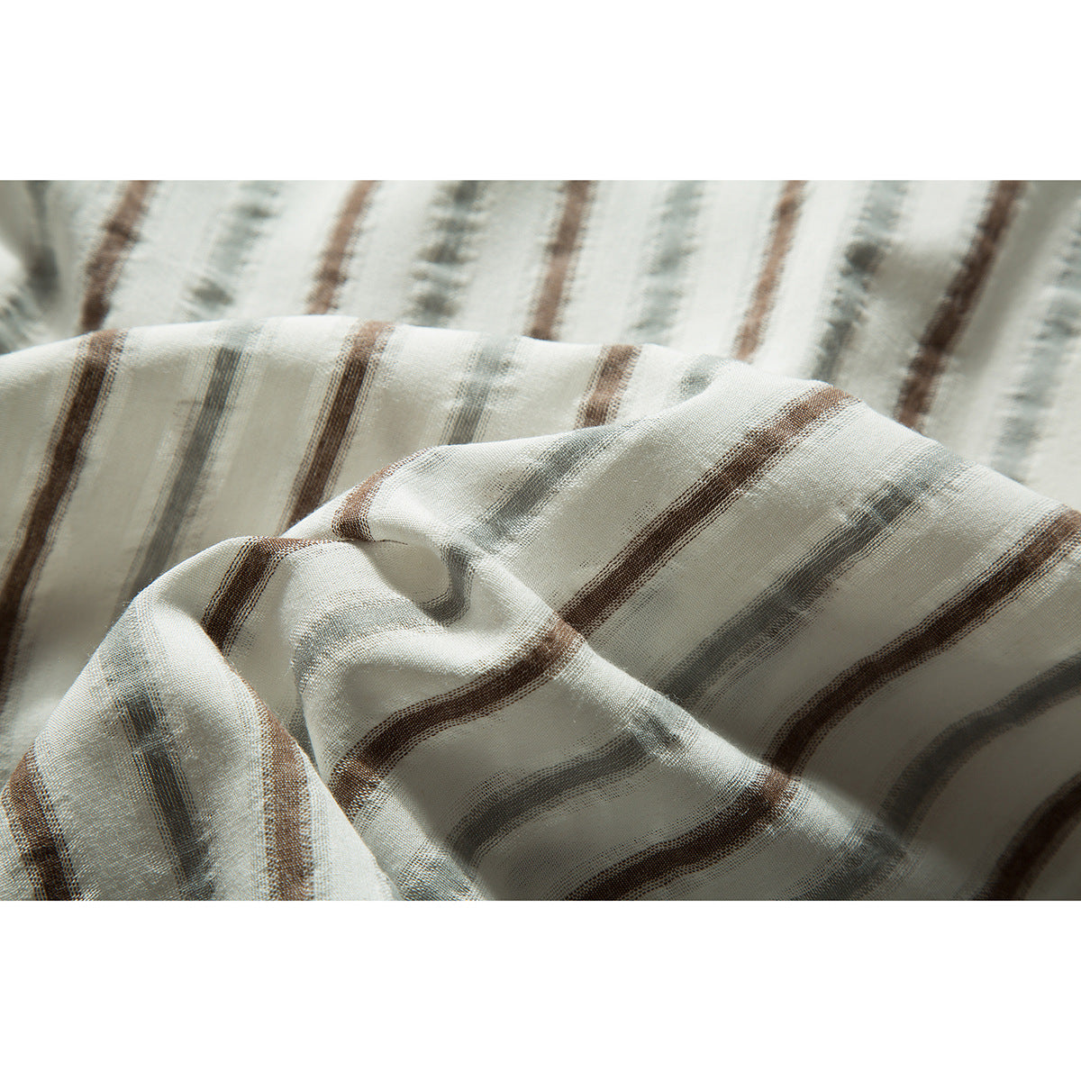 Close-up of the cream shirt fabric draped in folds, showing muted brown and gray stripes.