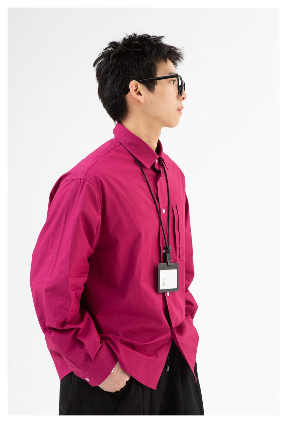 Close side view of a model wearing a magenta button-up shirt with a chest pocket and white buttons.