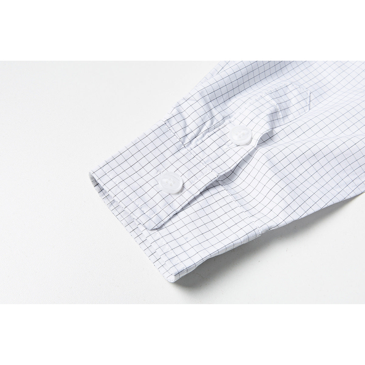 Close-up of a buttoned cuff on a white shirt with a fine gray grid check.