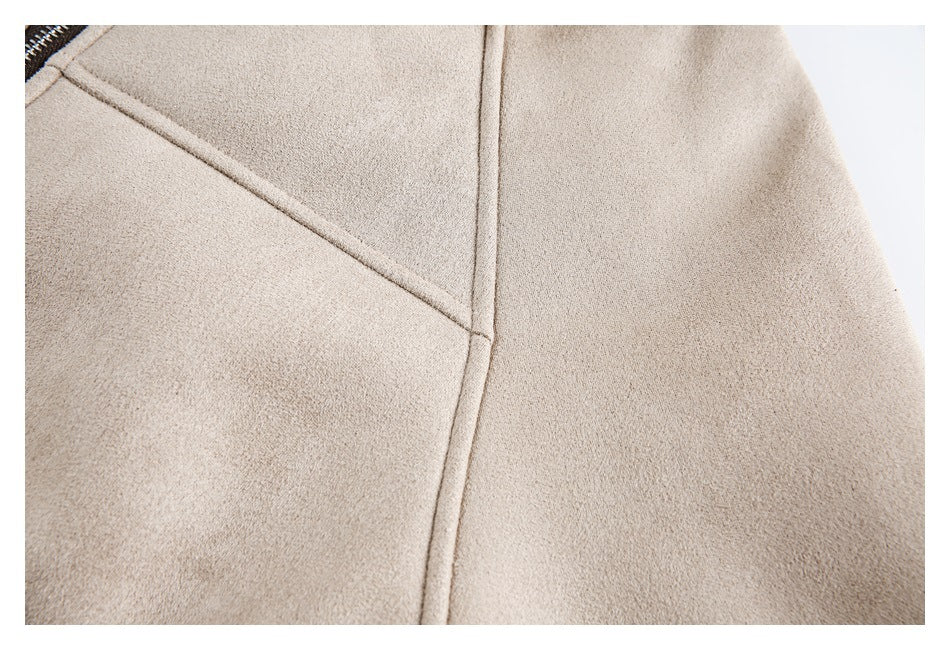 Close-up of a beige jacket showing intersecting stitched panel seams and a fine textured surface.