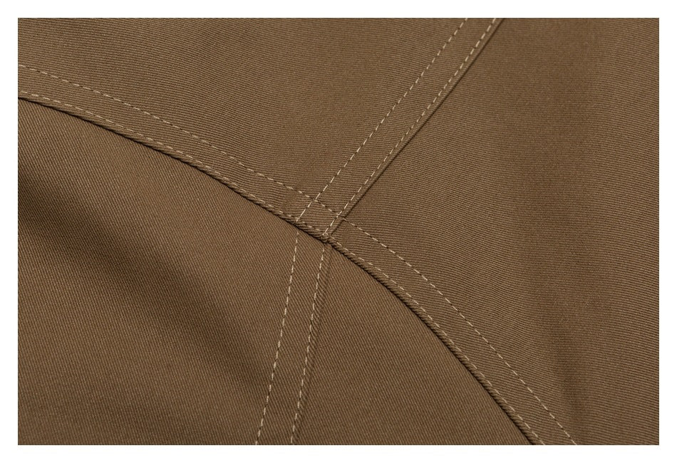 Close-up of intersecting stitched seams on brown fabric.