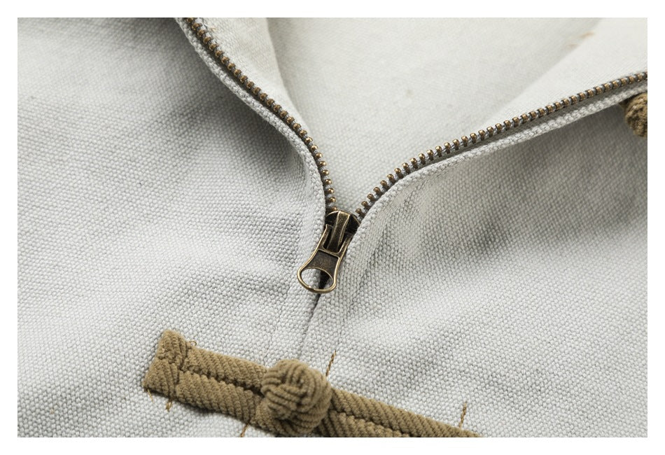 Close-up of the jacket's metal zipper and tan corduroy frog closure against pale gray fabric.