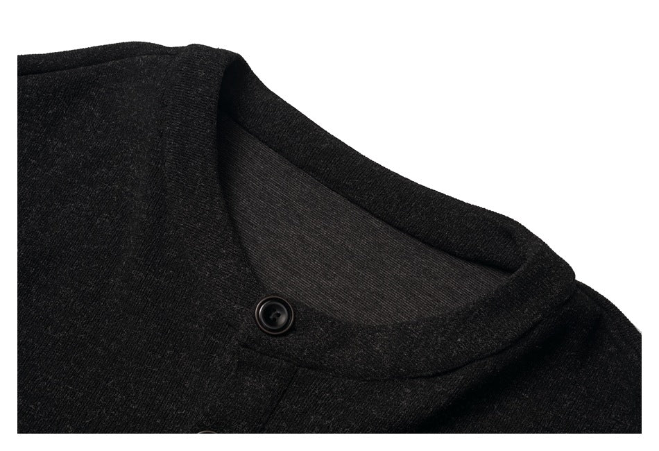 Close-up of a charcoal-black knit garment's rounded neckline and a black button.