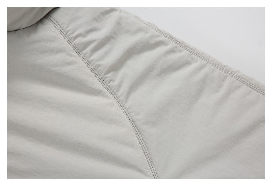Close-up of curved double stitching on light gray-beige jacket fabric.