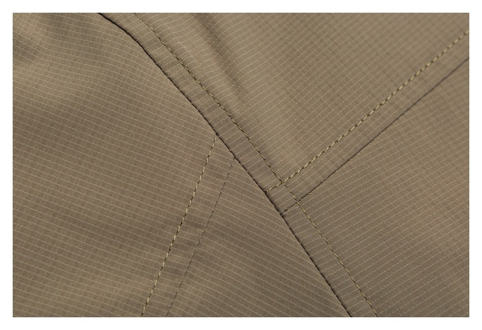 Close-up of taupe fabric with intersecting stitched seams and panel edges.