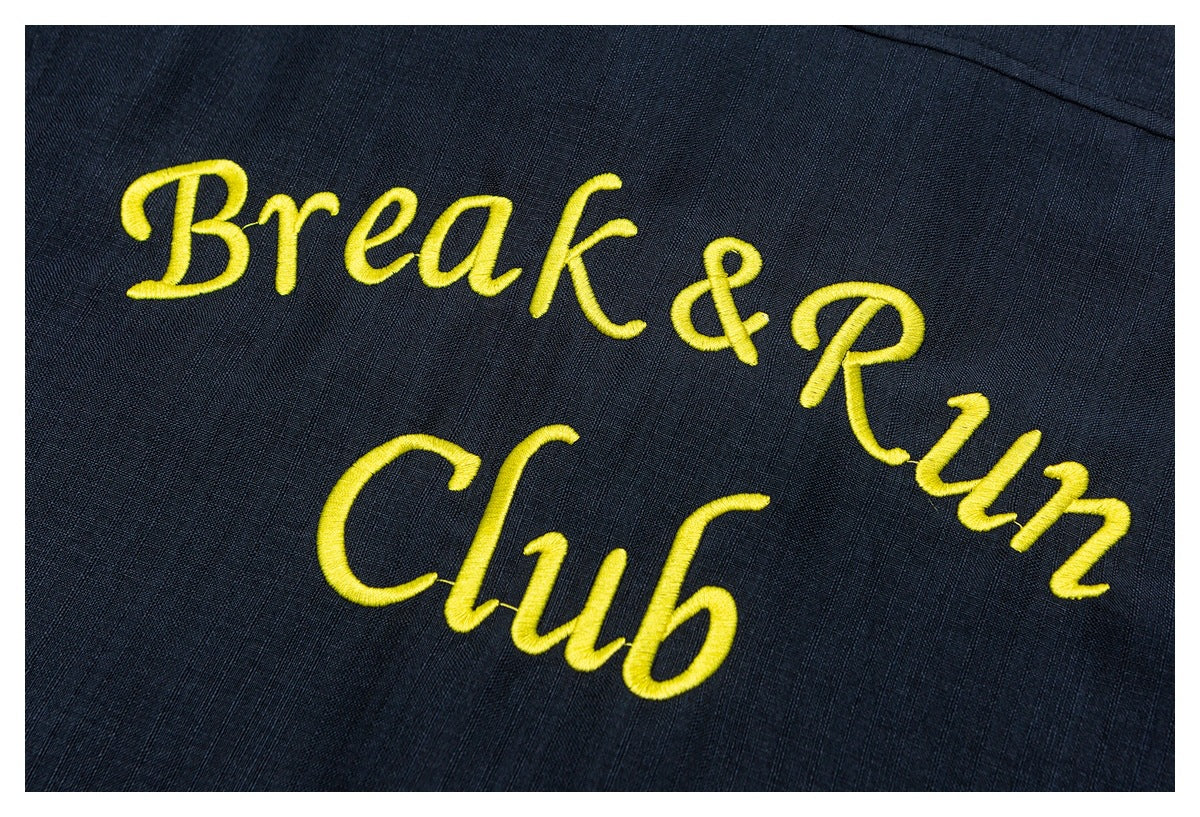 Yellow embroidered “Break & Run Club” lettering on dark navy textured fabric.