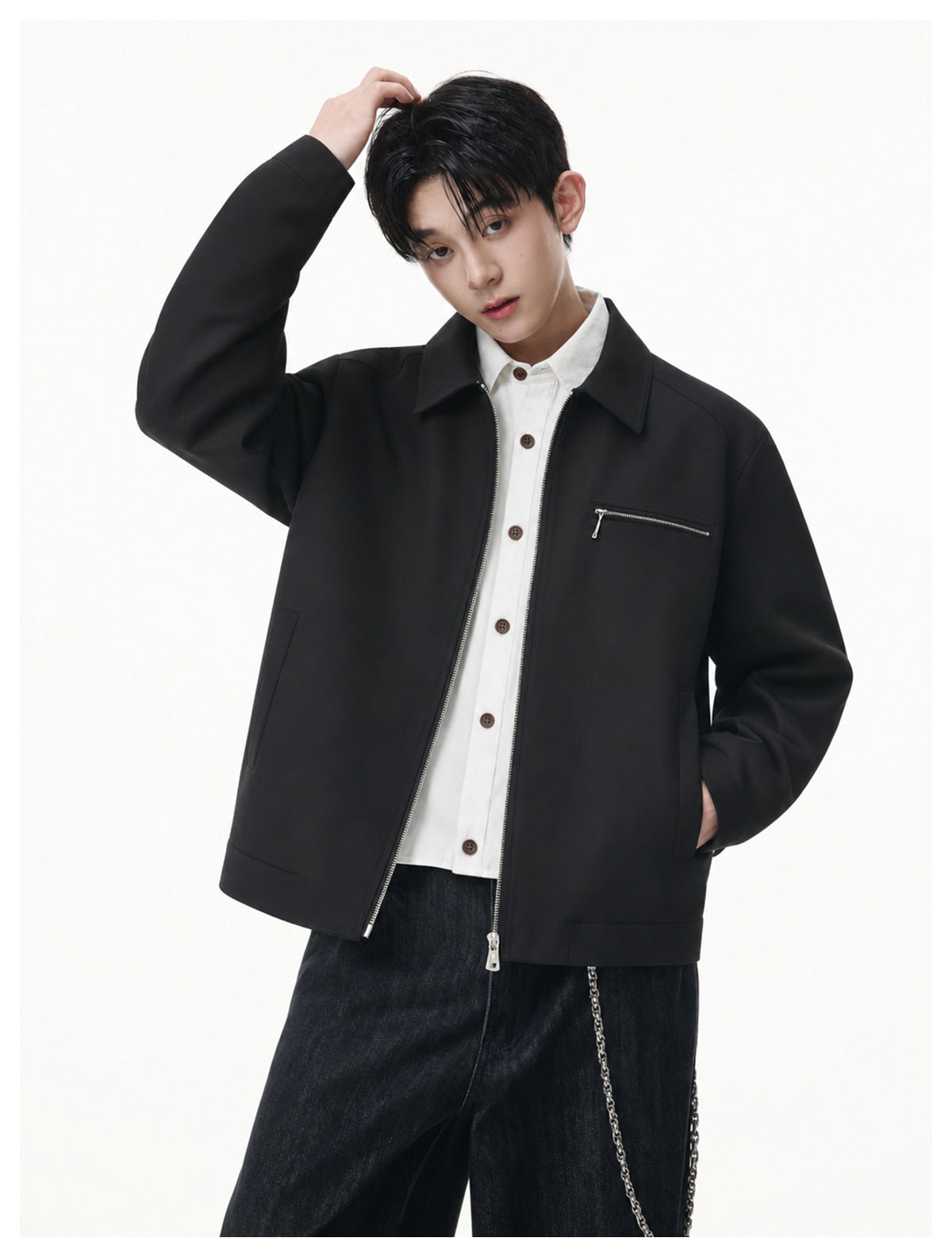 Model wearing an open black collared jacket with a chest zip pocket over a white button-up shirt.