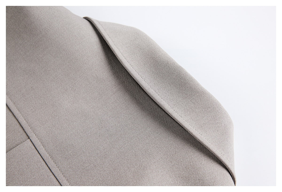 Close-up of taupe garment fabric with a curved folded edge and neat stitching.