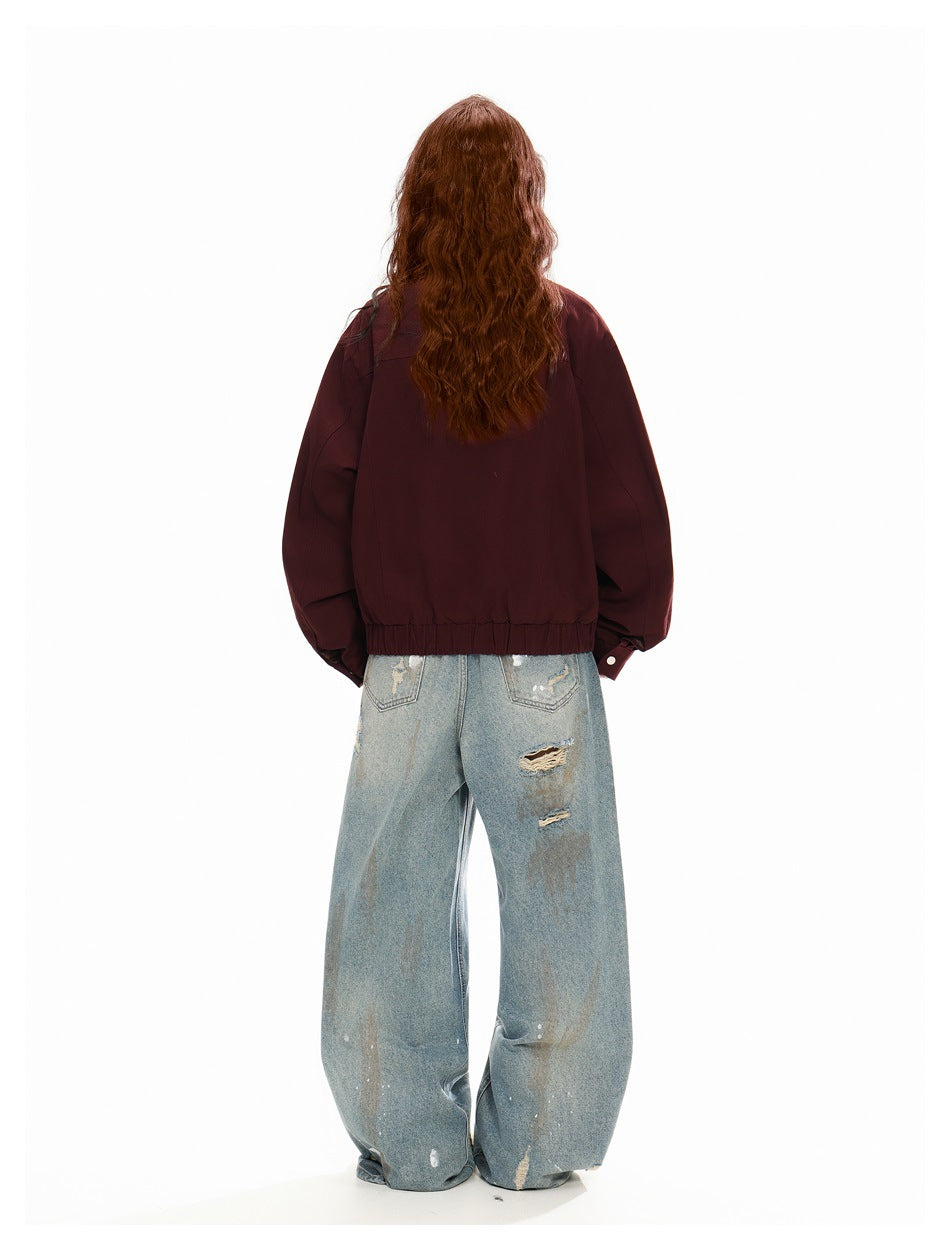 Back view of a model wearing a burgundy jacket with a gathered hem and light-wash wide-leg jeans.
