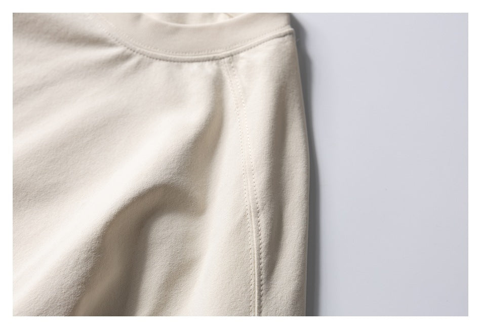 Close-up of an ivory garment's curved seam and stitching.