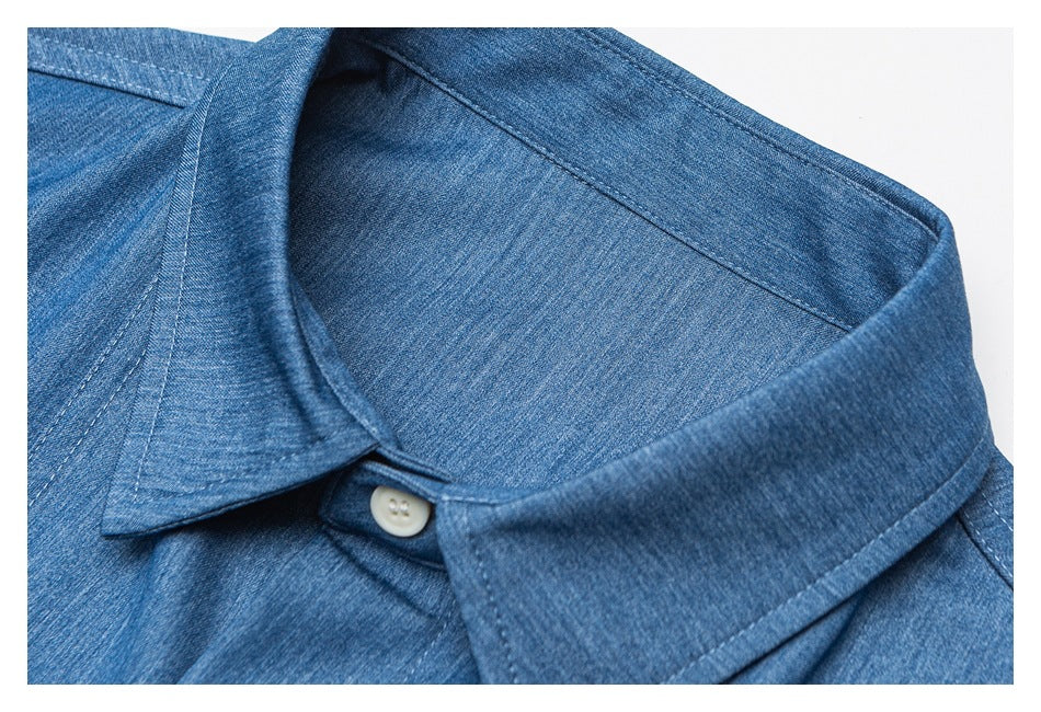 Close-up of the blue shirt’s pointed collar, collar stitching, and a white button.