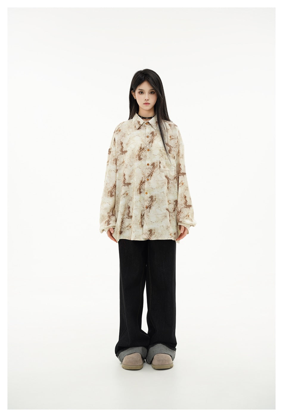 Model wearing oversized marbled beige and brown button-up shirt with black wide-leg jeans, front view