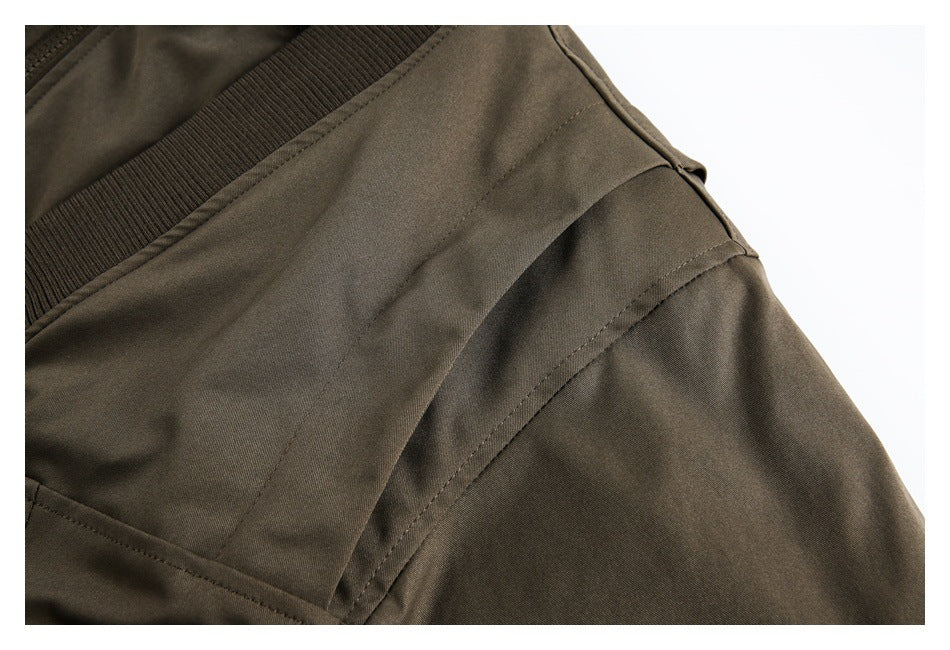 Close-up of the dark olive jacket's shoulder seams and sleeve construction.