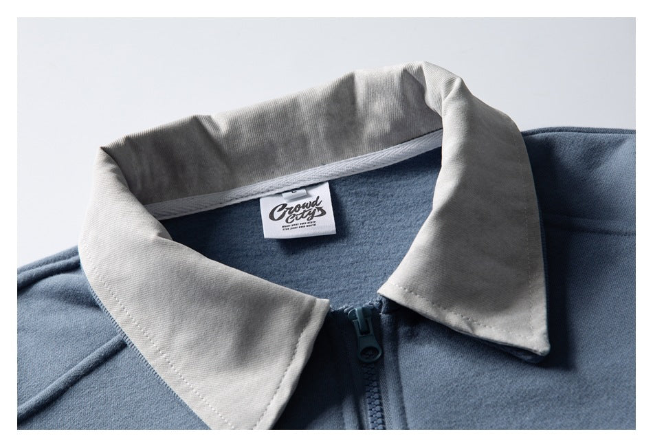 Close-up of a blue zip-up jacket's light gray pointed collar, zipper, and sewn-in neck label.