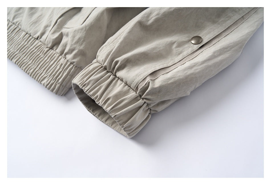 Close-up of a light beige garment with a gathered elastic edge and a metal snap button.