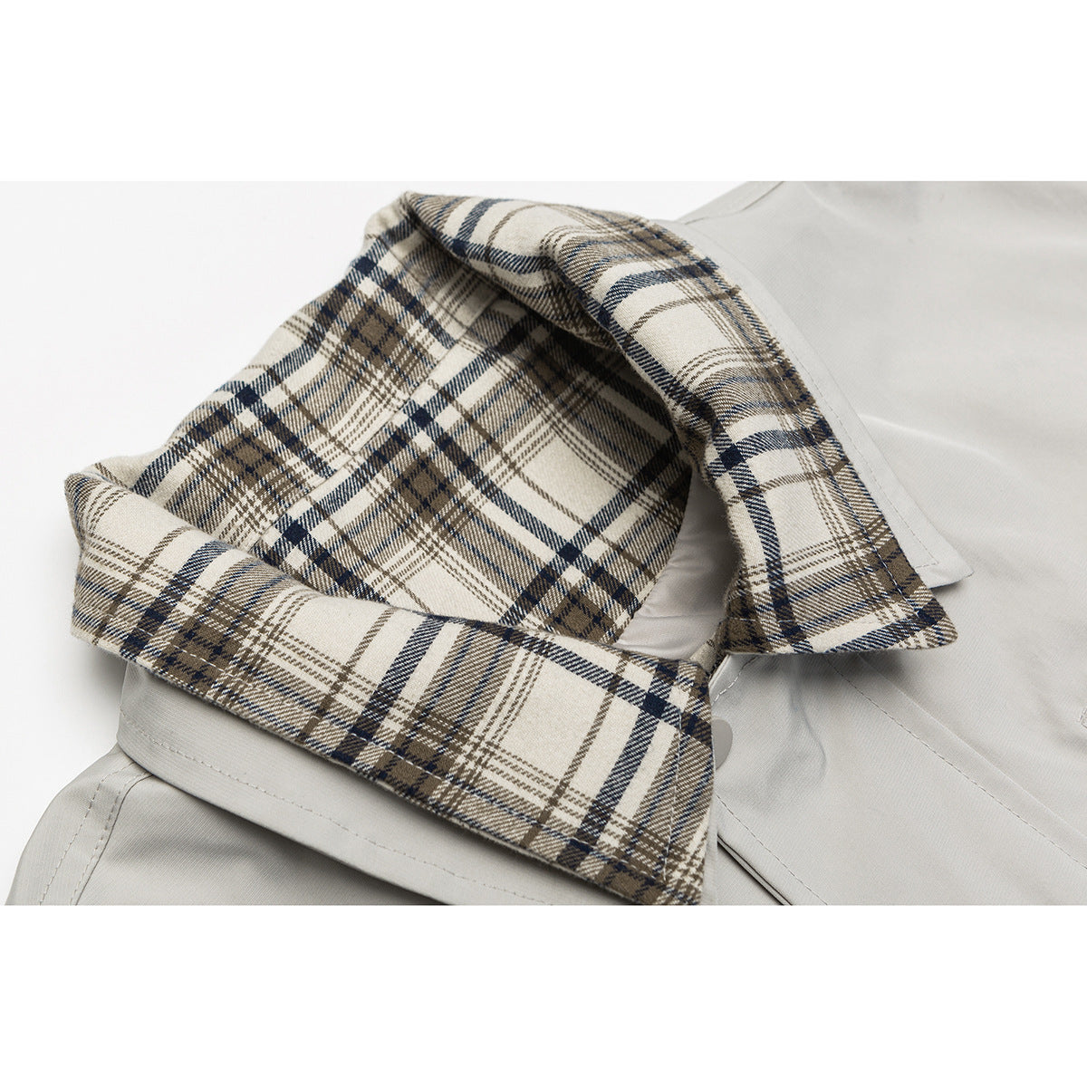 Close-up of a light gray jacket collar with beige, brown, and navy plaid lining.