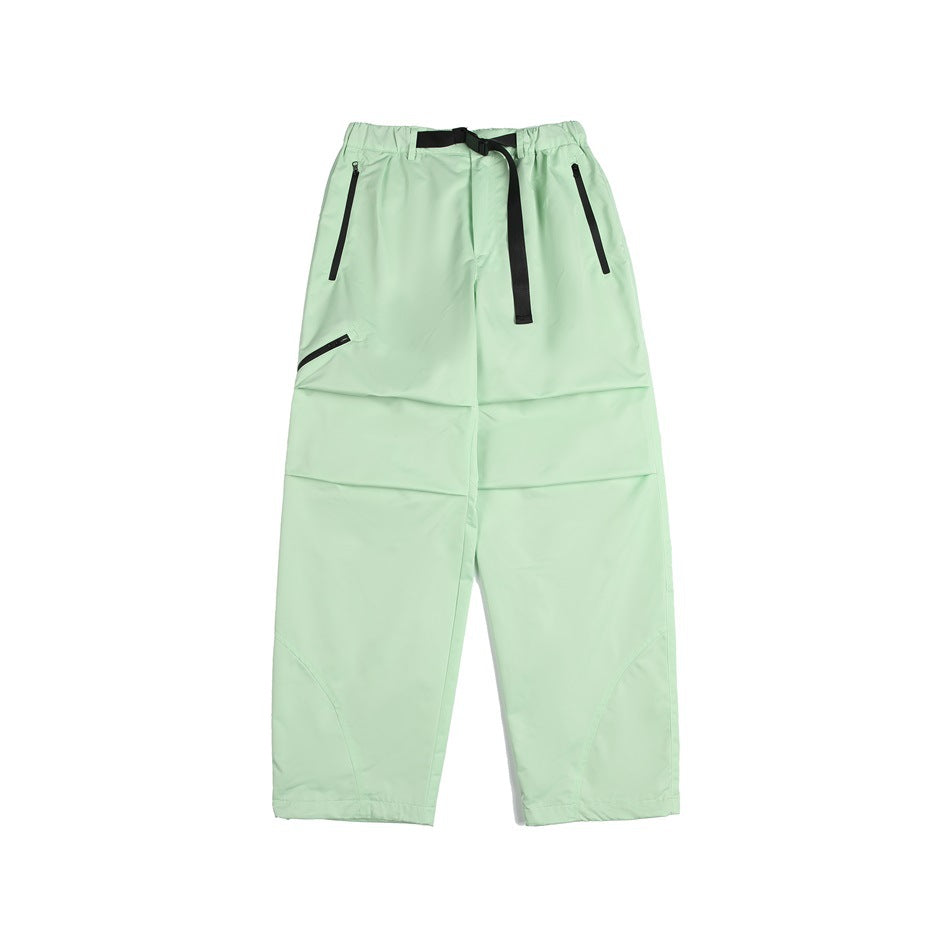 Light green wide-leg pants with black belt, zippered pockets, knee pleats and curved lower-leg seams, flat lay