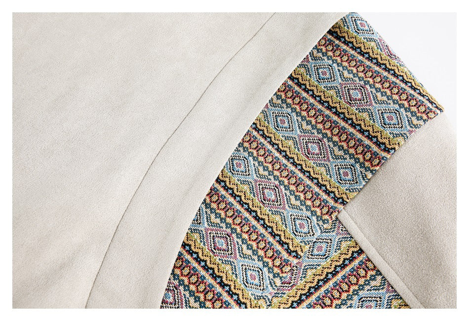 Close-up of a cream garment with a colorful geometric patterned panel along a curved edge.