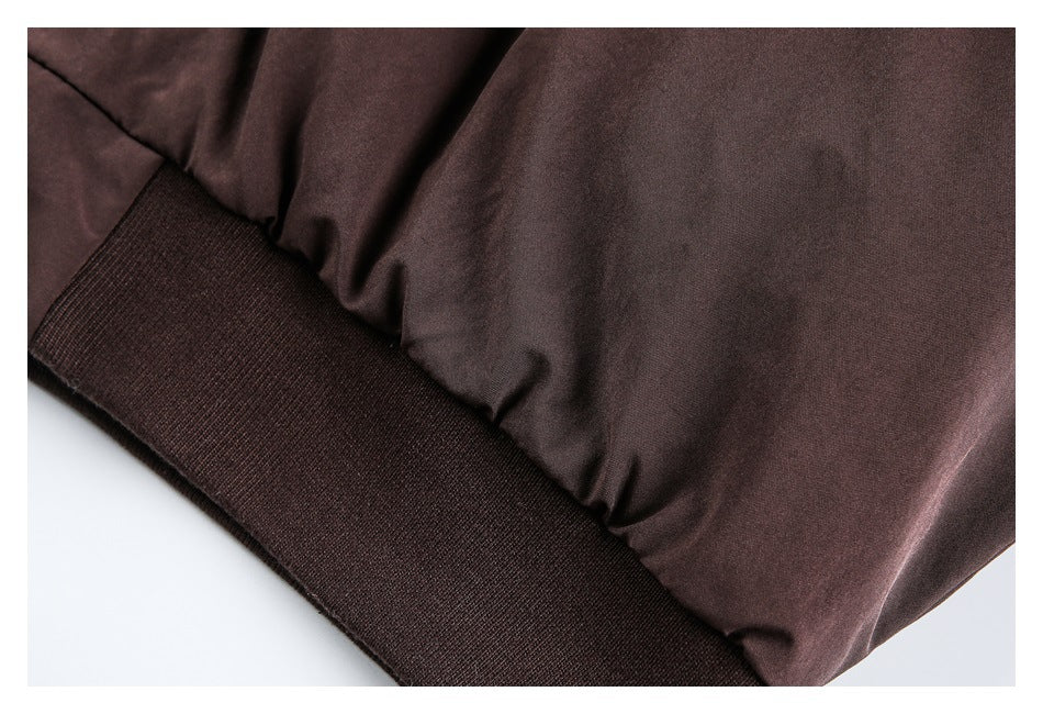 Close-up of a dark brown jacket sleeve gathered above a wide ribbed cuff.