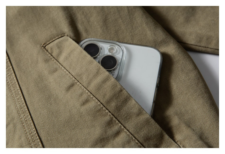 A smartphone partly tucked into a slanted pocket on an olive-khaki garment.