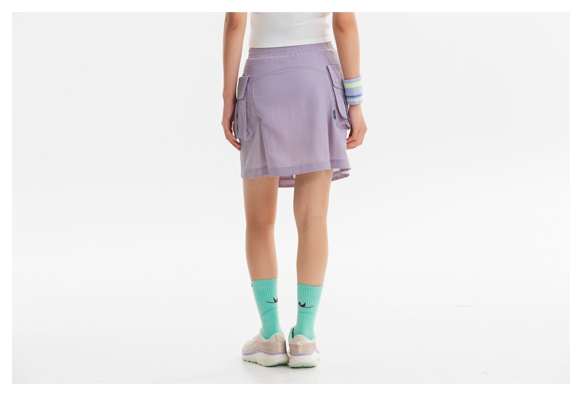 Back view of a model wearing a lilac cargo skirt with an elastic waistband and flap pockets.