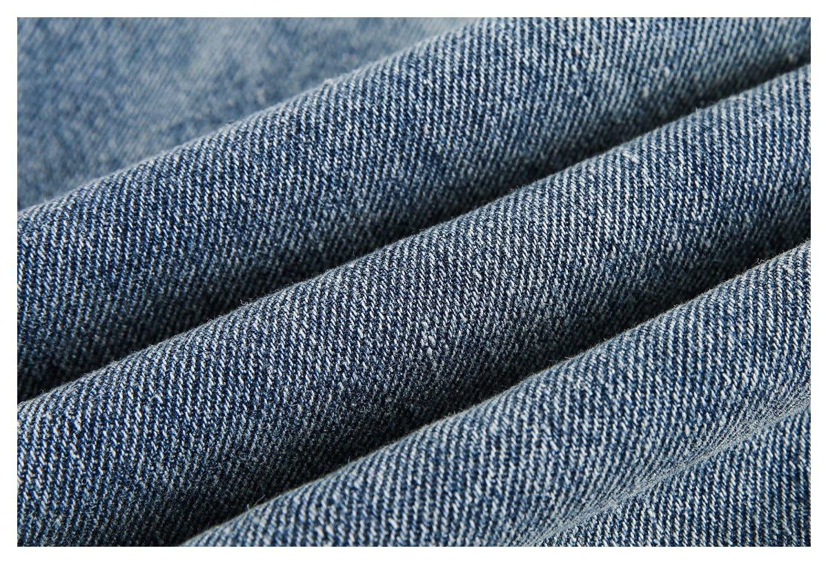 Macro close-up of blue denim fabric folded to show its diagonal weave and texture.