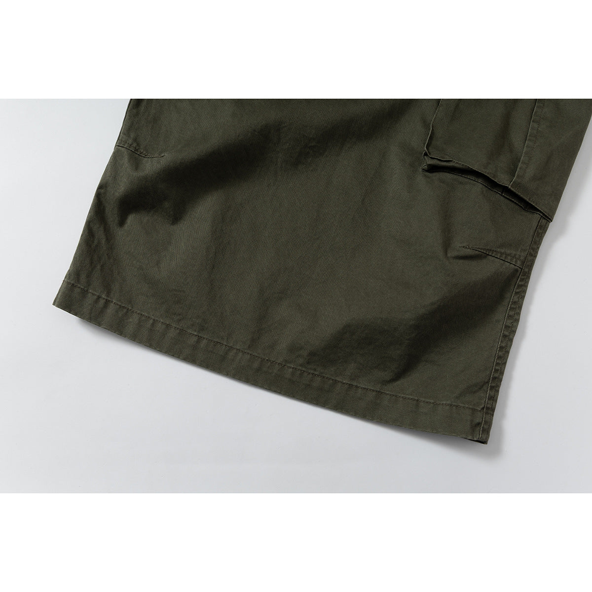 Close-up of the olive shorts' lower leg, showing the hem and side seam.