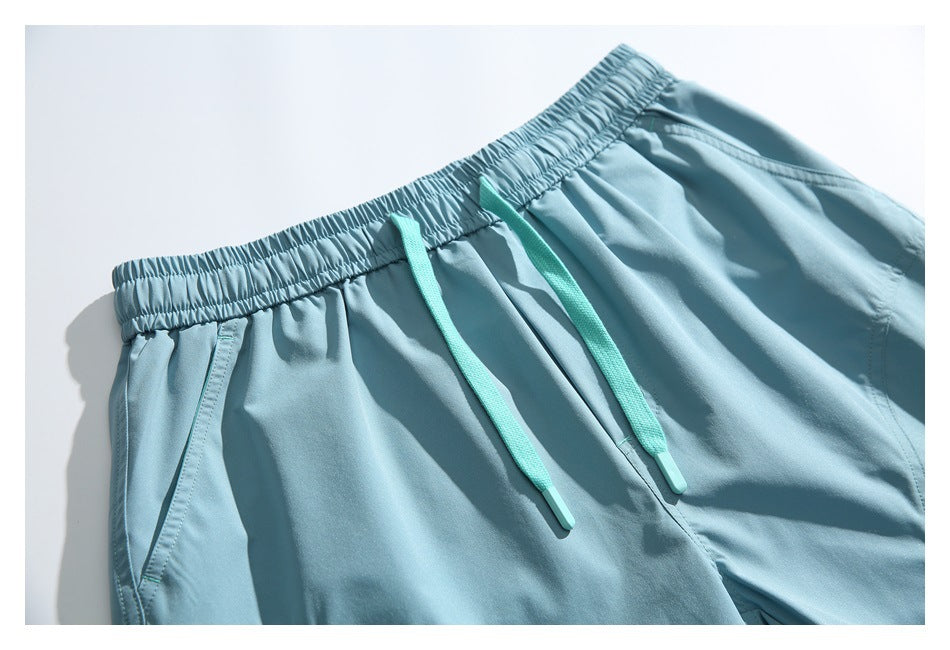 Close-up of pale blue shorts showing the gathered waistband, turquoise drawstrings, and front pockets.