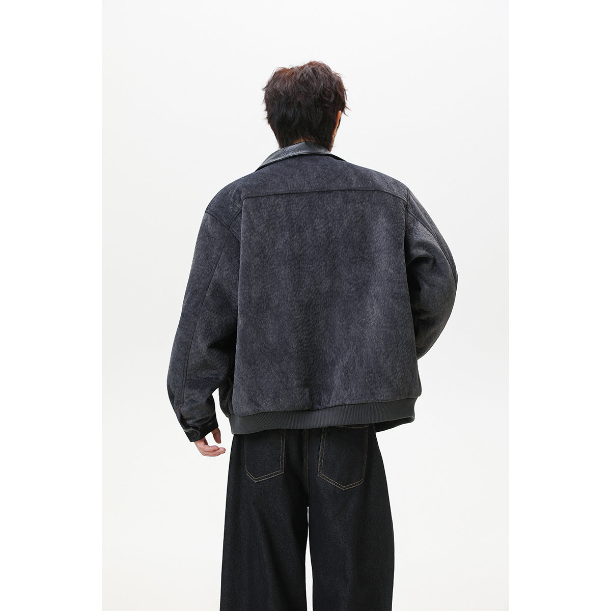Back view of a model wearing a dark charcoal textured jacket with a black collar and ribbed hem.