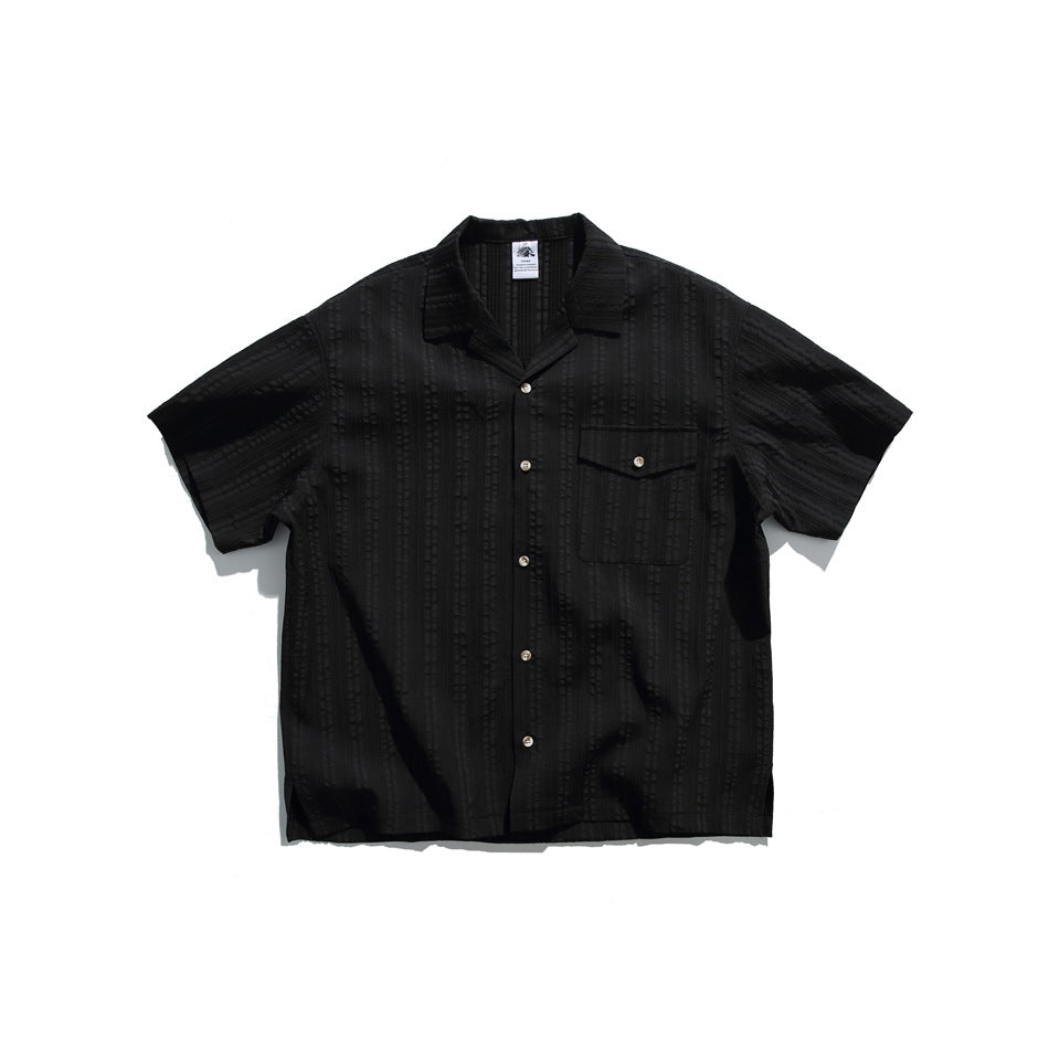 Black short-sleeve camp-collar shirt with textured stripes, button front and chest flap pocket, flat lay