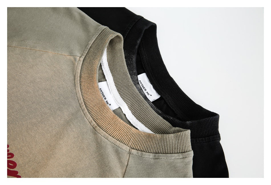 Close-up of beige and black crewneck tops showing their ribbed collars and neck labels.