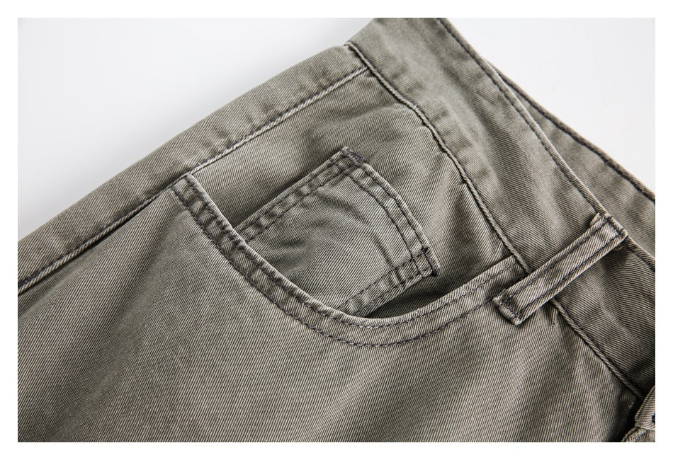 Close-up of gray-olive trousers showing a small coin pocket, curved front pocket, belt loop, and contrast stitching.