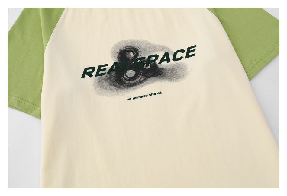 Close-up of the cream shirt front, showing green raglan sleeves and a dark graphic with English lettering.