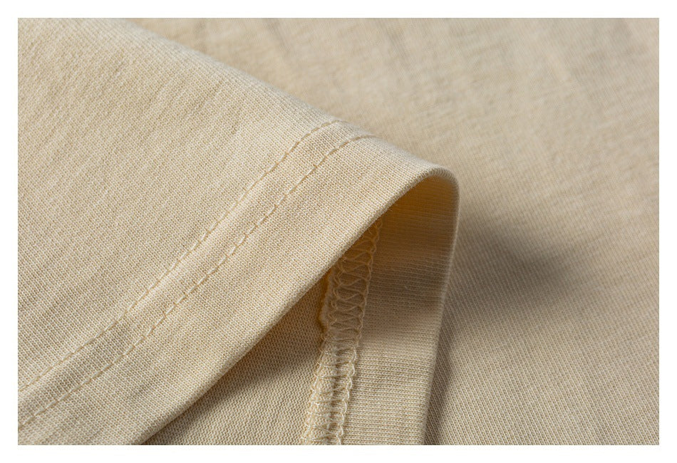 Close-up of a light beige garment sleeve hem, showing double stitching and the overlocked inner seam.