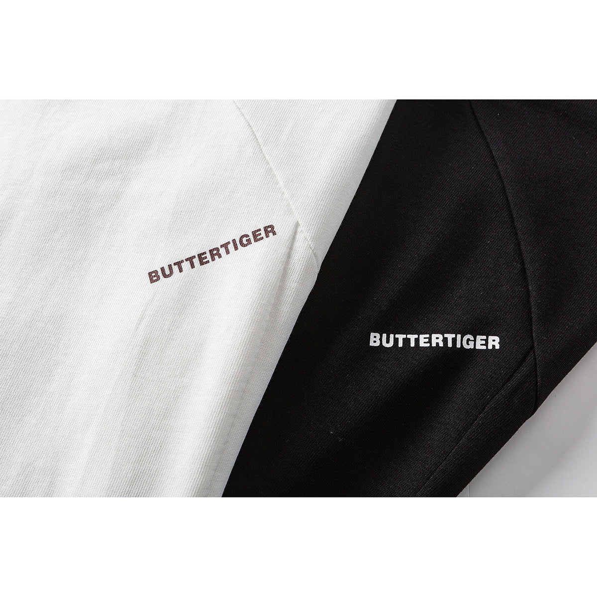 Close-up of white and black T-shirts with small BUTTERTIGER chest prints.