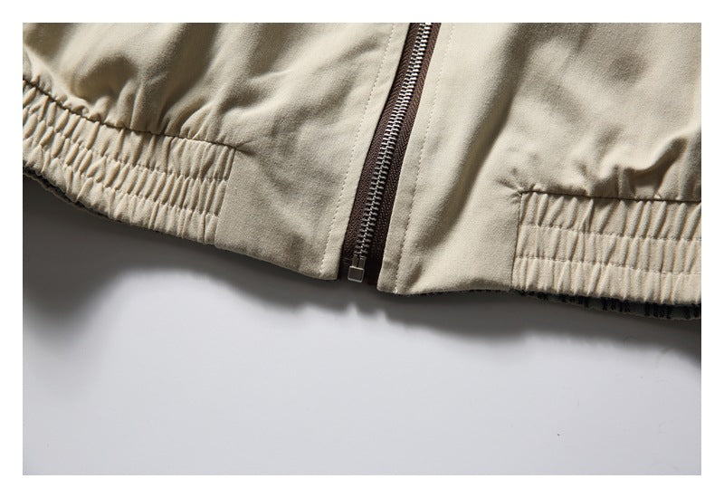 Close-up of a beige jacket's front zipper and gathered elastic hem.