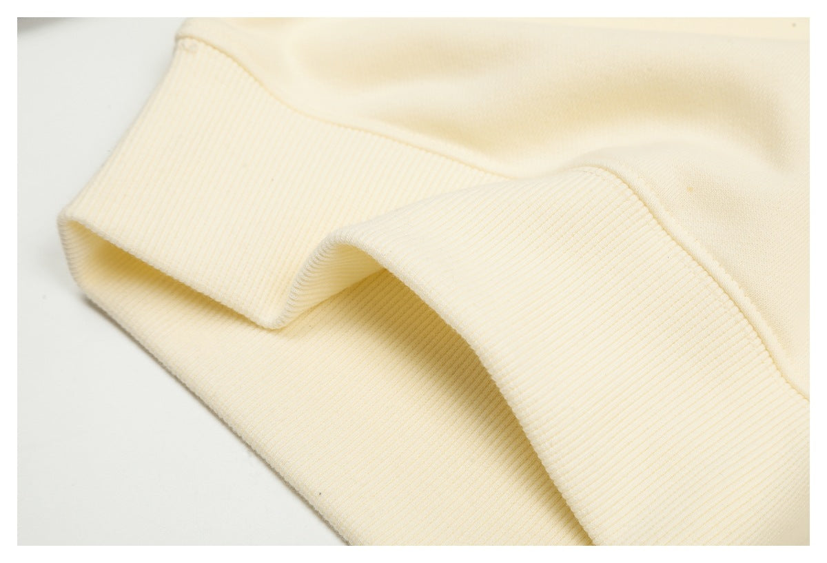 Close-up of a cream garment with a wide ribbed knit cuff or hem.