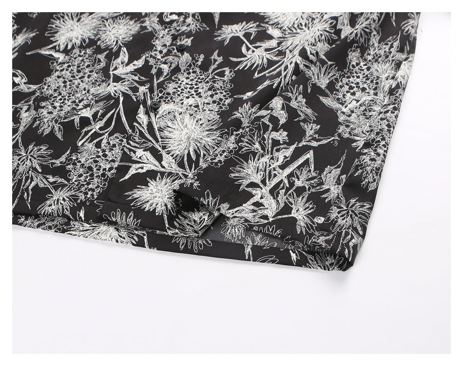 Close-up of the lower front of a black floral-print shirt, showing buttons and a hem.
