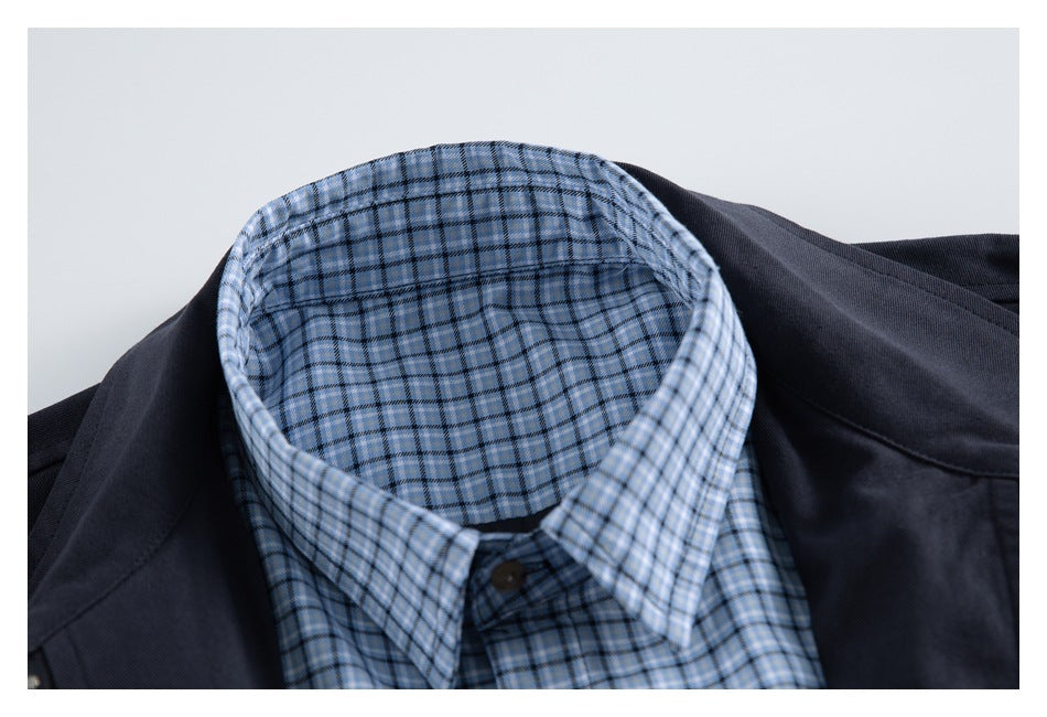 Close-up of a light blue plaid shirt collar beneath a dark navy jacket.
