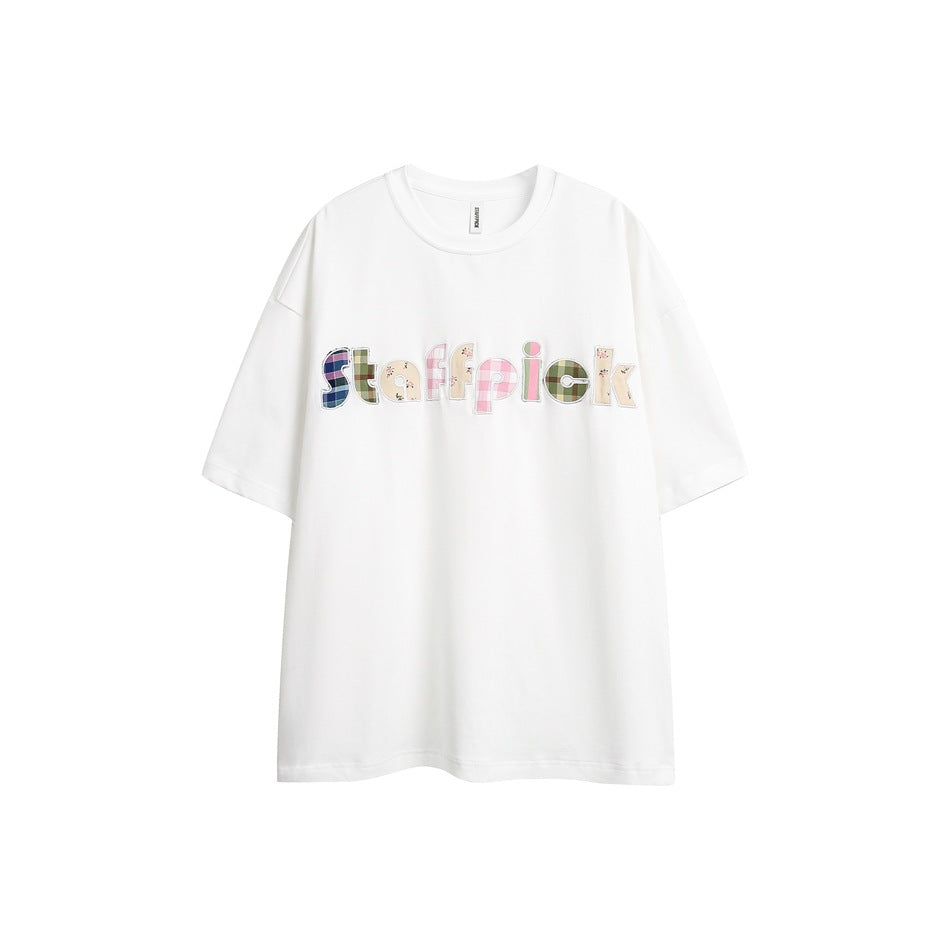 White short-sleeve crew-neck T-shirt with plaid and floral appliqué letters across the chest, flat front view