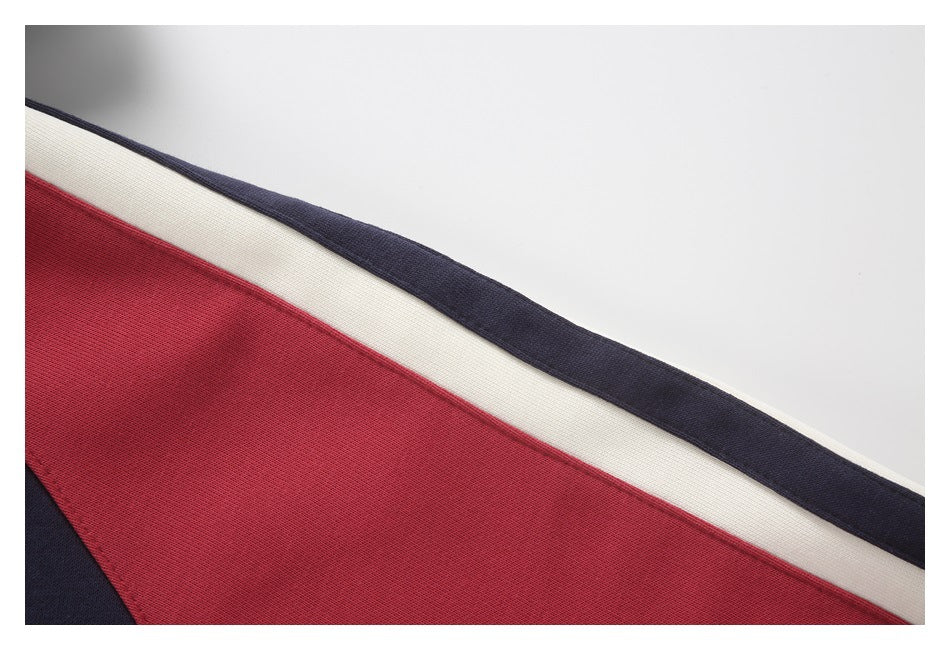 Close-up of a garment with diagonal red, ivory, and navy panels.