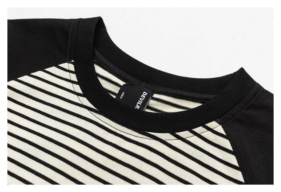 Close-up of a black ribbed crew neckline with cream-and-black striped fabric and an inside label.