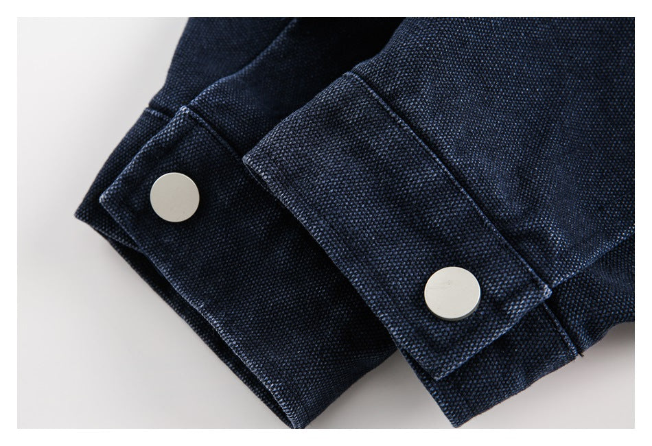 Close-up of two silver snap buttons on cuffs of dark navy textured fabric.