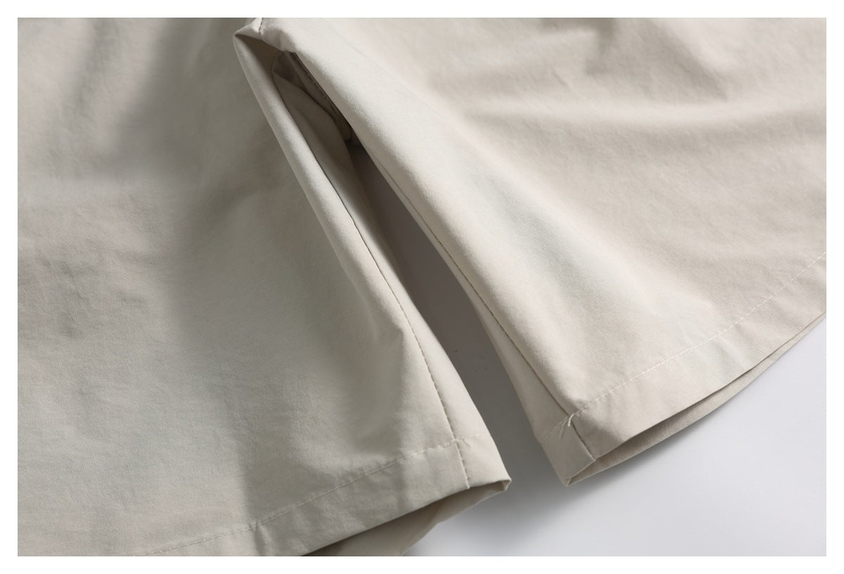 Close-up of the stitched hems and side opening of light beige shorts.