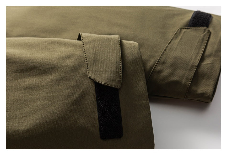 Close-up of an olive jacket sleeve cuff with a fabric tab and black hook-and-loop closure.