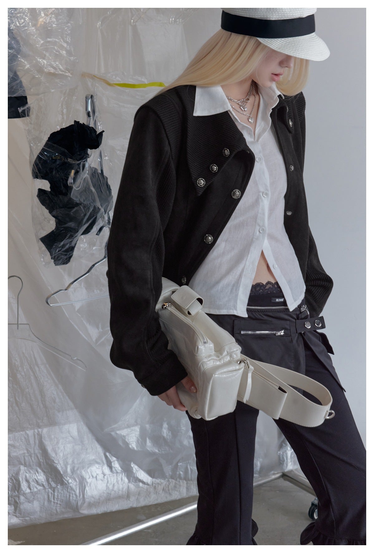 Close view of a model wearing a black buttoned jacket over a white shirt, paired with black trousers.
