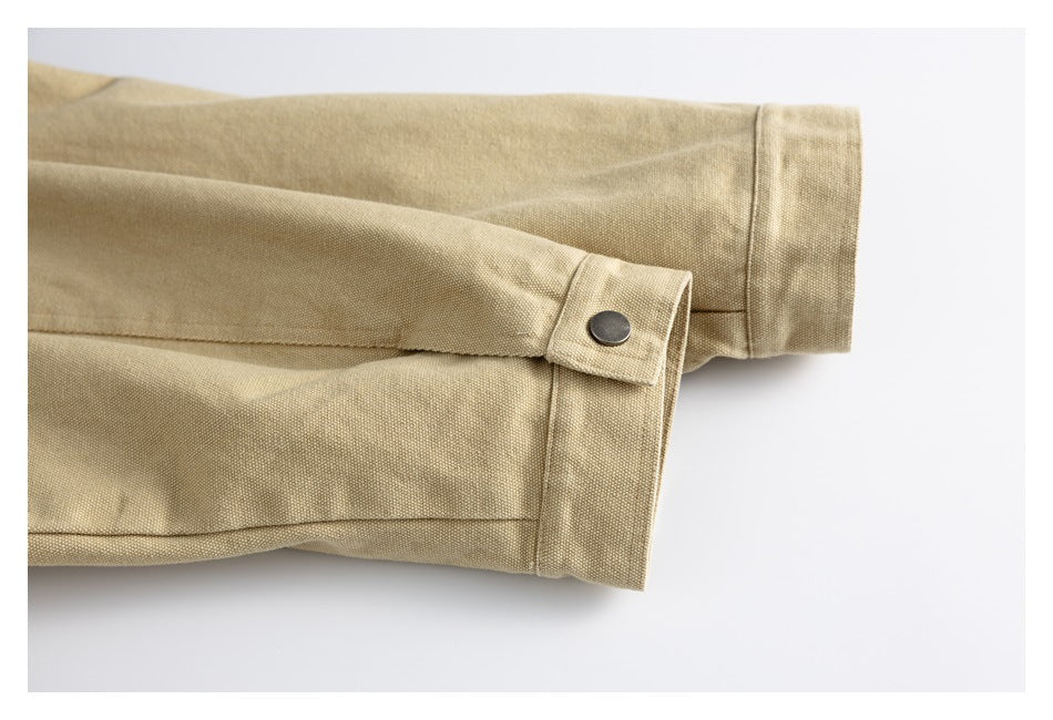 Close-up of a tan jacket sleeve cuff with a dark metal snap fastening.