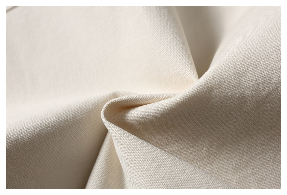 Close-up of ivory fabric folded to show its fine, even woven texture.